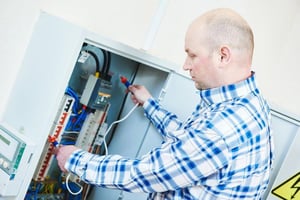 Electrician inspecting an electrical control panel during hands-on training, representing planning electrical continuing education (CE) classes for career advancement.