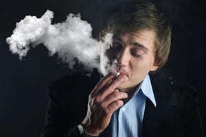 Adult man smoking a cigarette in a dark setting, highlighting factors related to cigarette freshness and product quality.