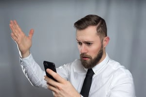 Concerned man looking at his phone, illustrating the warning signs of increasingly sophisticated online dating scams targeting men.