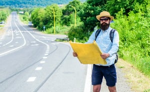 Bearded man holding a map on an open road, symbolizing career planning and creating a personal roadmap for career growth.
