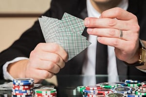 Casino player holding playing cards over a table covered with colorful betting chips during an ongoing game.