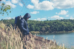 Person walking beside a peaceful lake, representing the importance of environment in addiction recovery.