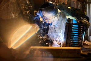 Welder working amid toxic fumes and sparks, illustrating welding exposure and mesothelioma risks.