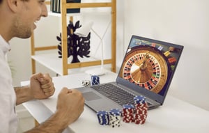 Man playing an online casino game on this laptop while his laptop is on the table.