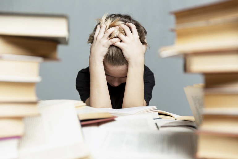 Student sitting stressfully at a study table while dealing with academic burnout.