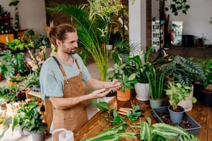 Gardener caring for potted plants and inspecting containers, illustrating common container gardening mistakes that can harm plants.
