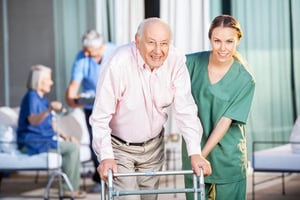 Elderly man receiving assistance from a caregiver in a trusted assisted living home.