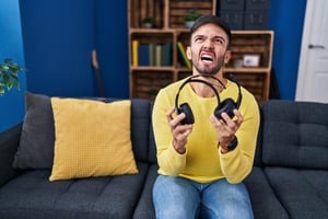 A frustrated gamer taking off his headset in anger, illustrating the toxicity and frustration of online voice chat.