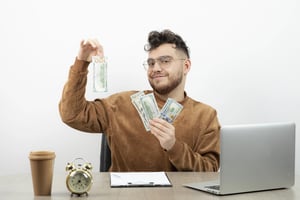 Man managing money at an office desk, reviewing cash.