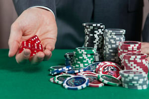 A man holding dice in hand and poker chips on the table