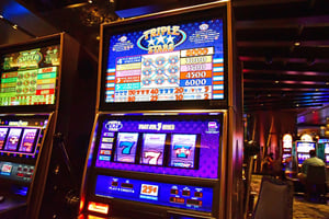 Slot machine with brightly lit reels and payout schedules displayed inside a casino.