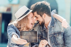 Happy couple smiling while taking a selfie outdoors.