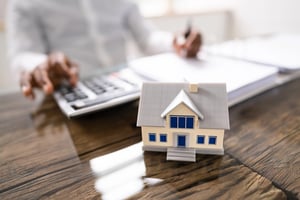 Property tax and home loan calculations with financial paperwork, a calculator, and a house model.
