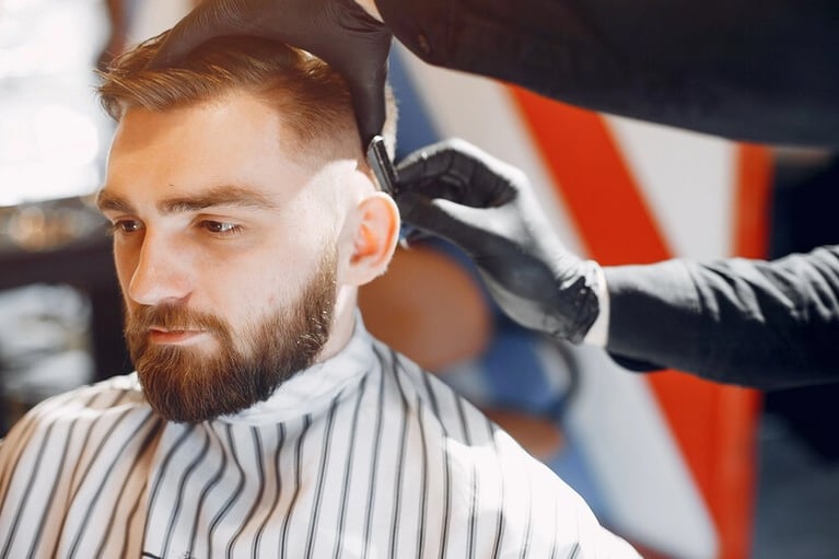 A male client getting a fresh haircut from a barber.