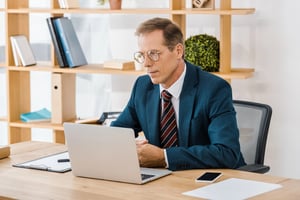 Man reviewing property tax documents on a laptop in an office.