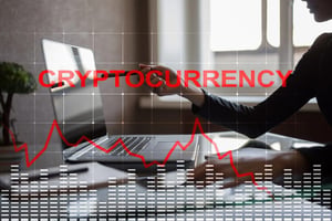 A man on a laptop with a red market chart showing cryptocurrency.