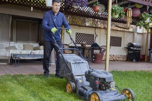 Man tending to a garden with regular lawn care, pruning, and maintenance.