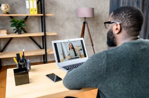 Man sitting in a modern workspace using a laptop during a working visit and remote collaboration.