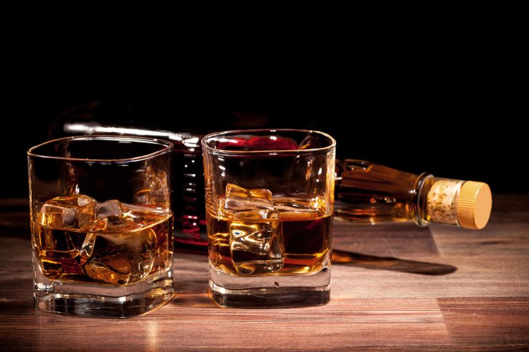 Glasses and bottle of whiskey on a wooden surface.