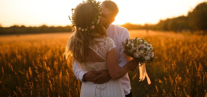 Newlywed kissing in the field