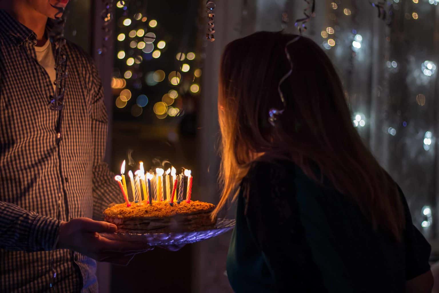 A woman looking at cake with lit candles