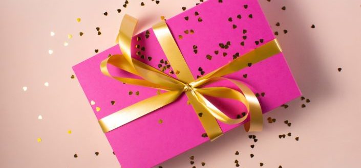 A pink gift box wrapped in gold ribbon