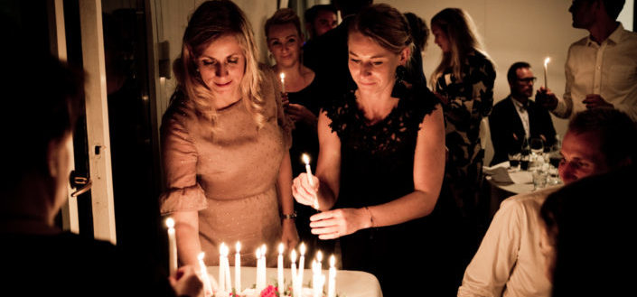 Two women holding candles by a cake