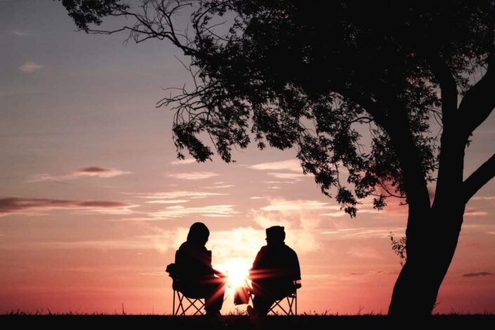 two people watching the sunset while talking