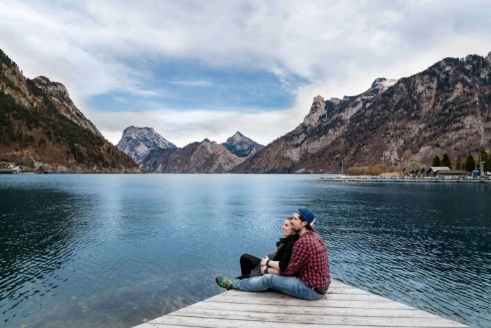 Couple sitting on a platform beside a lake.