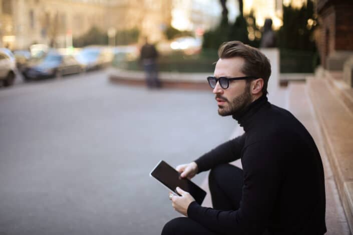 Man thinking while sitting along the sidewalk.