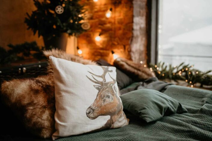 white throw pillow printed with a deer design on a cozy couch