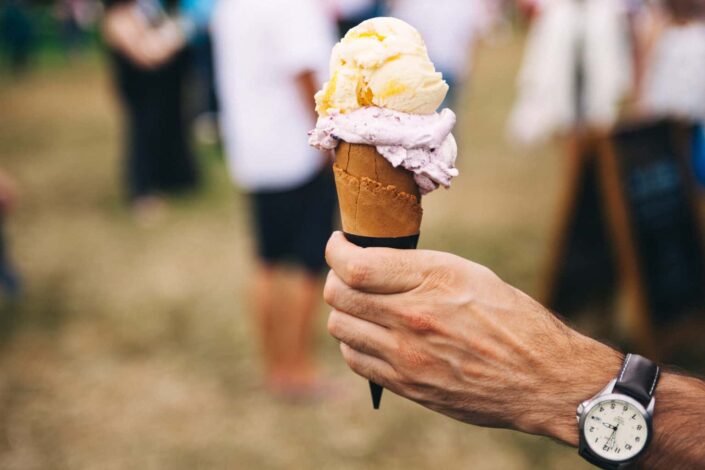 man's hand holding a cone of ice cream