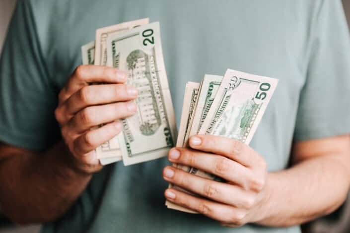 Crop man counting dollar bills