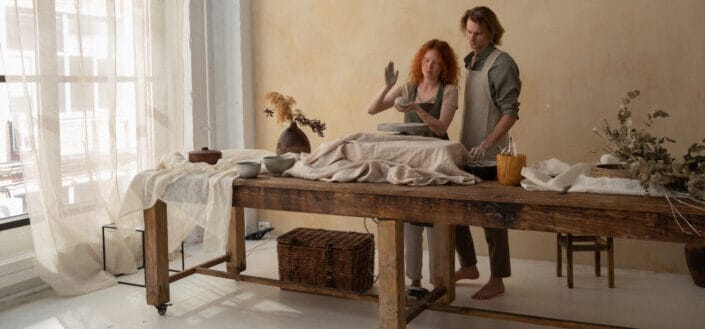 man and woman behind a table doing pottery