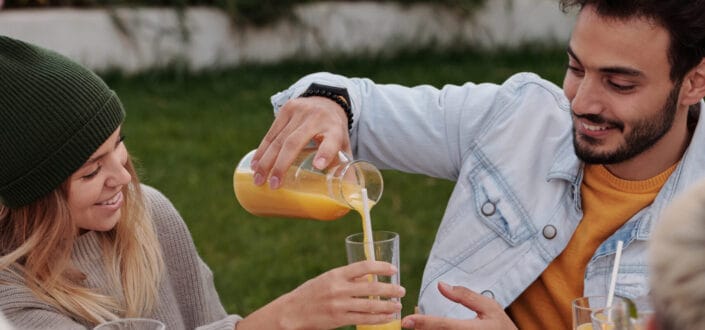 man pouring juice from a pitcher to a woman glass