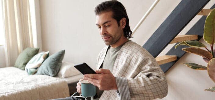 Man looking at his cellphone while having coffee