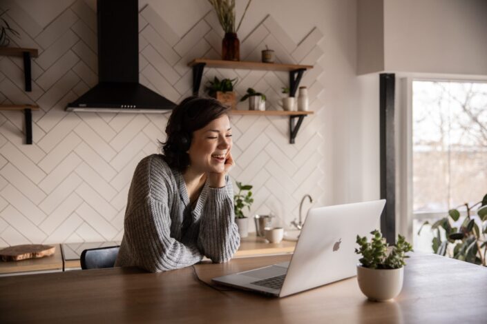 a woman laughing in front of her laptop