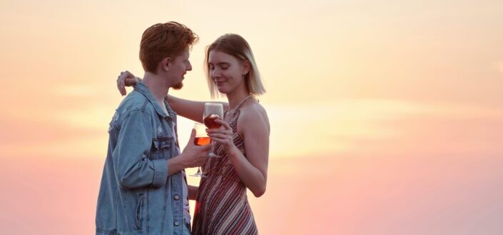 couple holding each other while holding wine glasses