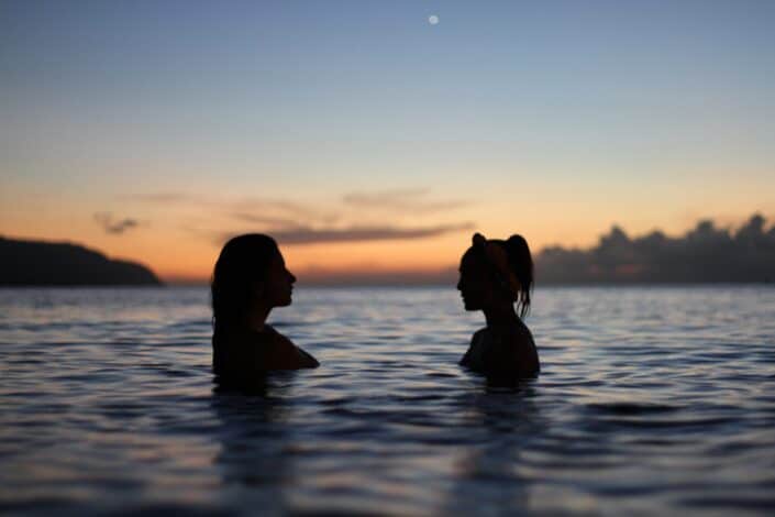 silhouette of two women in the middle of the ocean