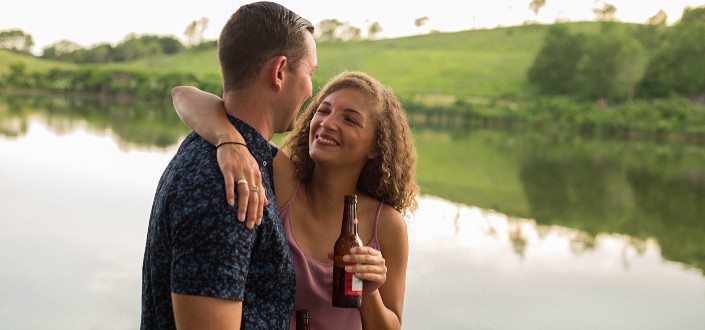 A couple drinking beer by a river