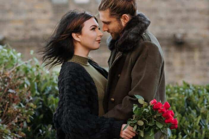 Woman holding a bouquet of roses about to kiss a man