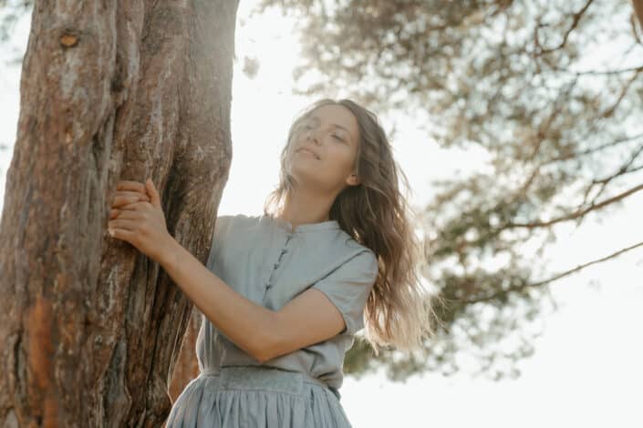 A woman in blue holding onto a tree