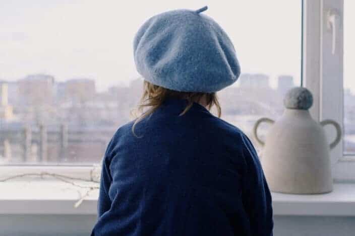 Little girl in beret looking out window 