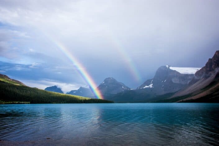 A rainbow over a lake through the mountains.