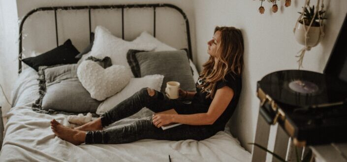 Woman sitting on bed while having coffee