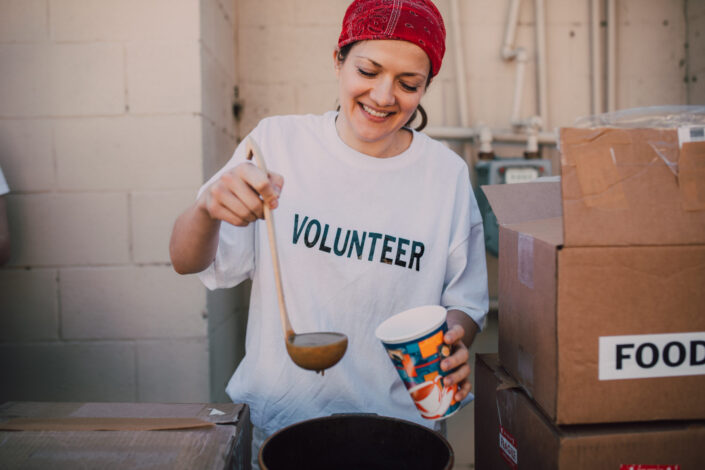 A volunteer woman scooping a soup.