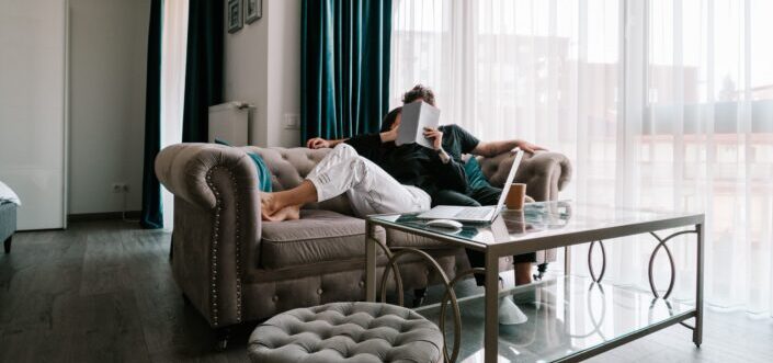 Couple cuddling on a couch and reading together.