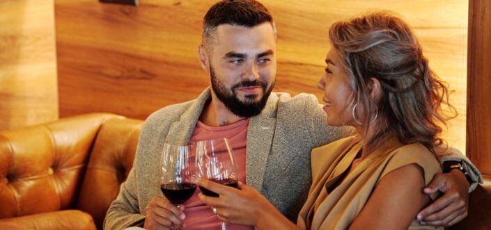 Couple drinking wine while sitting on a couch.