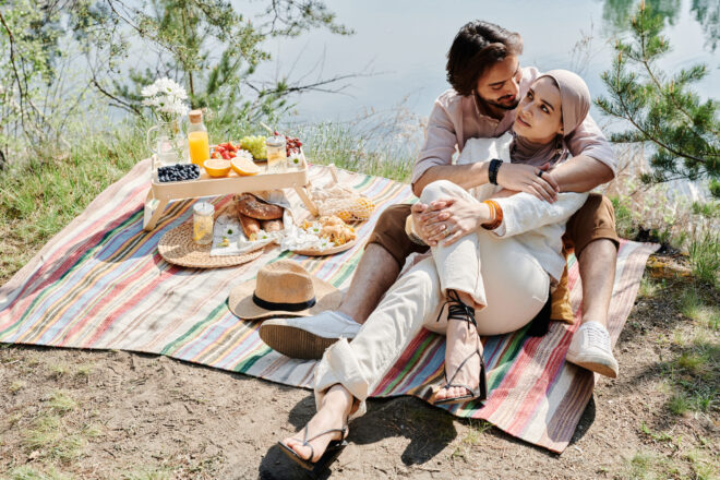 Couple having a picnic date beside a lake.