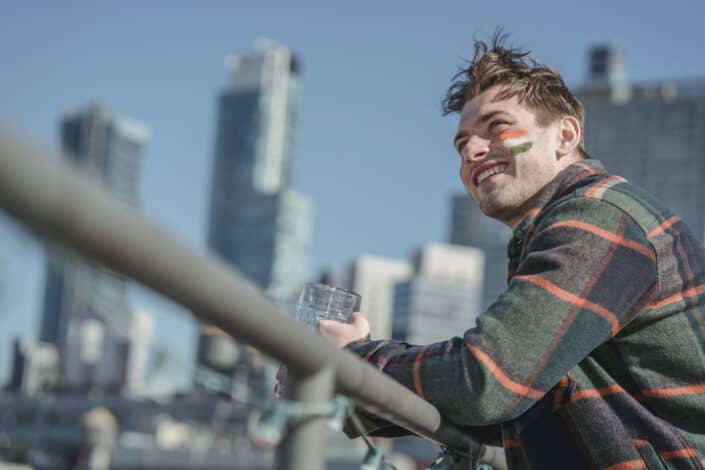 Man smiling while looking away and leaning on the railing outdoors.